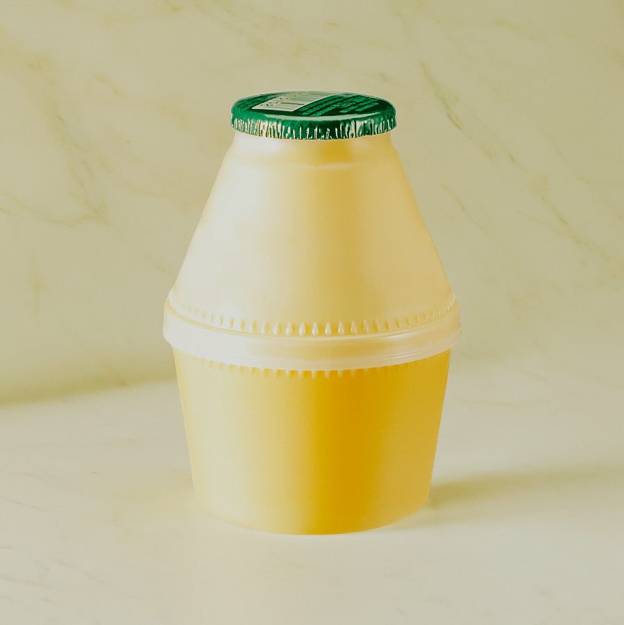 A yellow container with a green lid, resembling a bottle of banana milk.