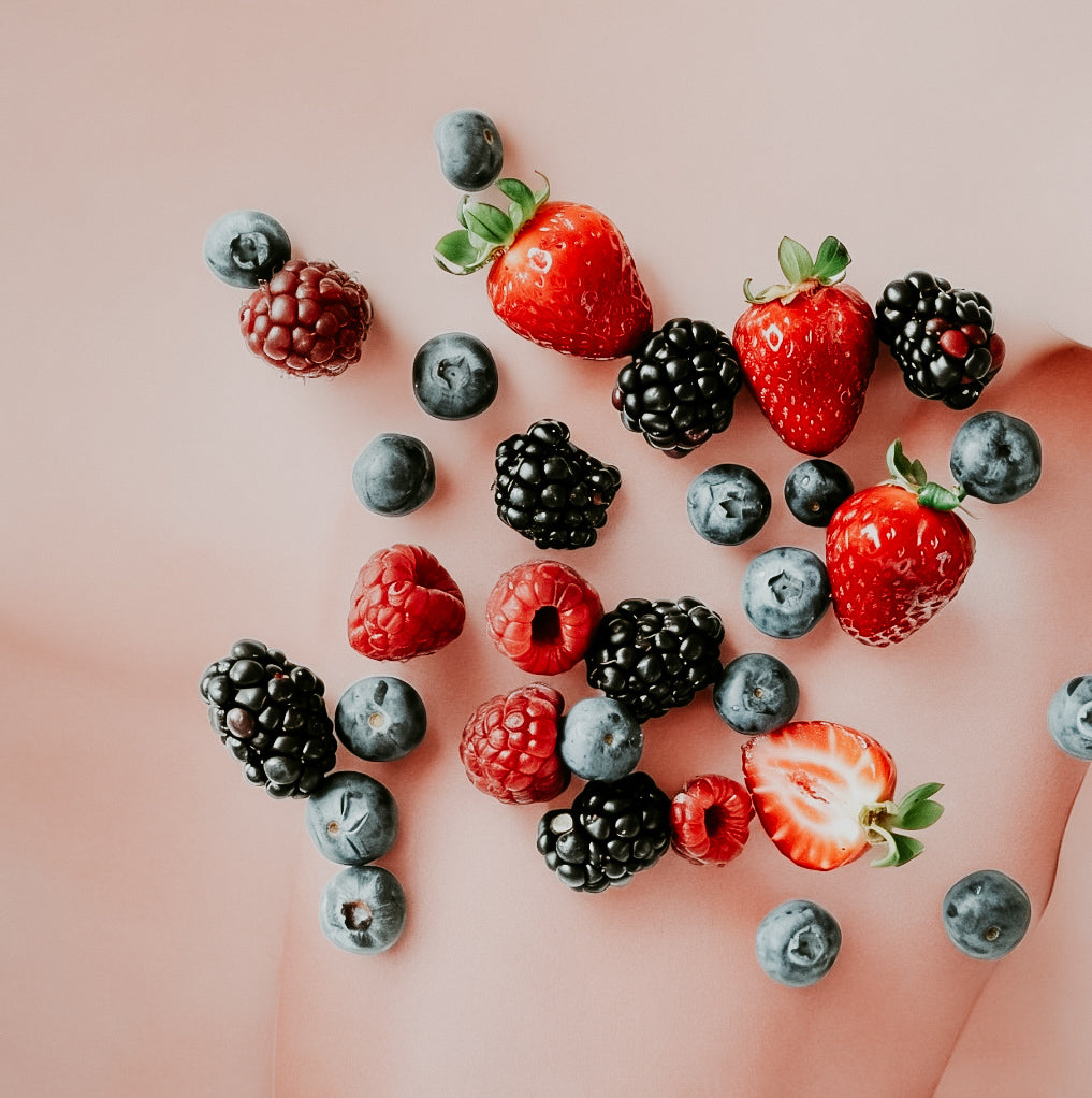 An assortment of fresh berries including strawberries, blueberries, blackberries, and raspberries scattered on a surface.