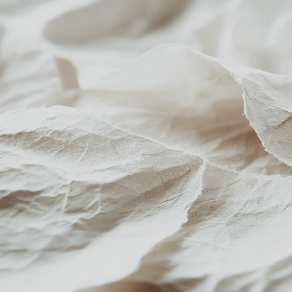 A close-up image of crumpled white paper, emphasizing texture and the soft, minimalist theme of the fragrance oil.