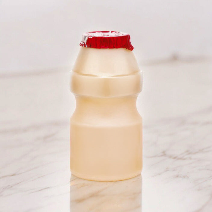 A a bottle of Yakult with a red cap on a marble surface.