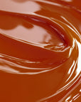 A close-up image of a smooth, dark orange-colored candle dye