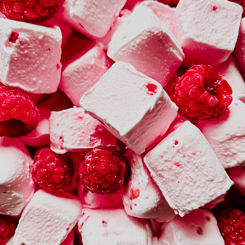 A close-up image of pink marshmallow fluff with pieces of fresh raspberry, showcasing a sweet and indulgent dessert.