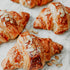 A photo of delicious almond croissants with sliced almonds and powdered sugar on top, indicating a fragrance oil inspired by the dessert.