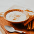A bowl of Arroz Con Leche (Spanish Rice Pudding) served in a ceramic bowl with cinnamon sticks and a spoon on the side.