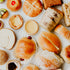 A variety of freshly baked Asian goods including croissants, buns, bread rolls, and tarts displayed on a surface.