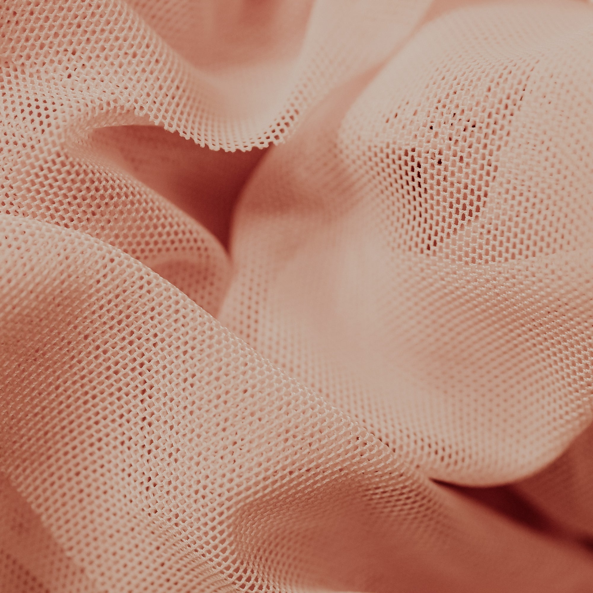 A close-up image of a peach colored textile with a mesh texture.