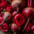 Beets and red roses arranged together on a dark background