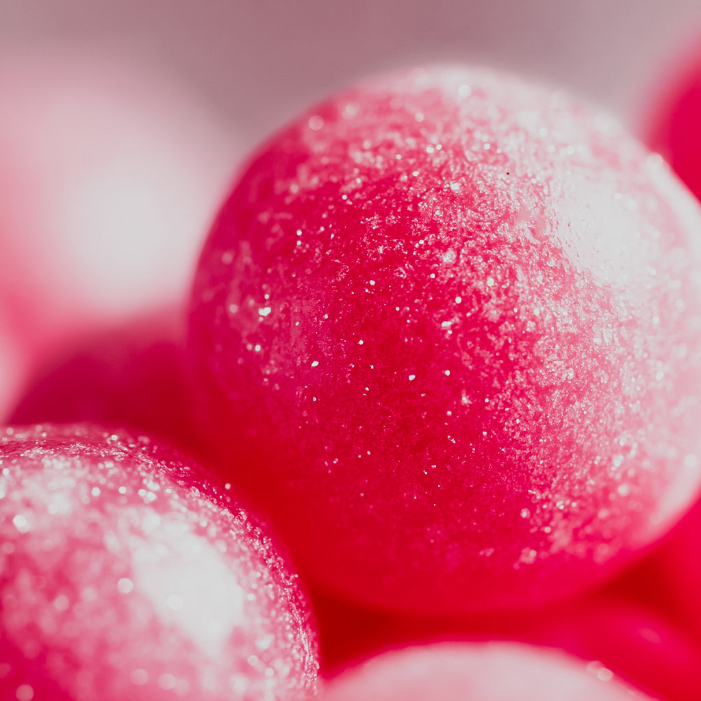 Close-up of pink bubblegum candies with a glittery sugar coating.