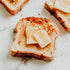Slices of toasted bread with pieces of butter on top, placed on a marble surface.