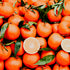 A pile of fresh California clementines with leaves still attached, some cut in half to reveal the interior.