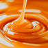 A close-up image of caramel syrup being drizzled into a pool of caramel liquid, showing a smooth, glossy texture.
