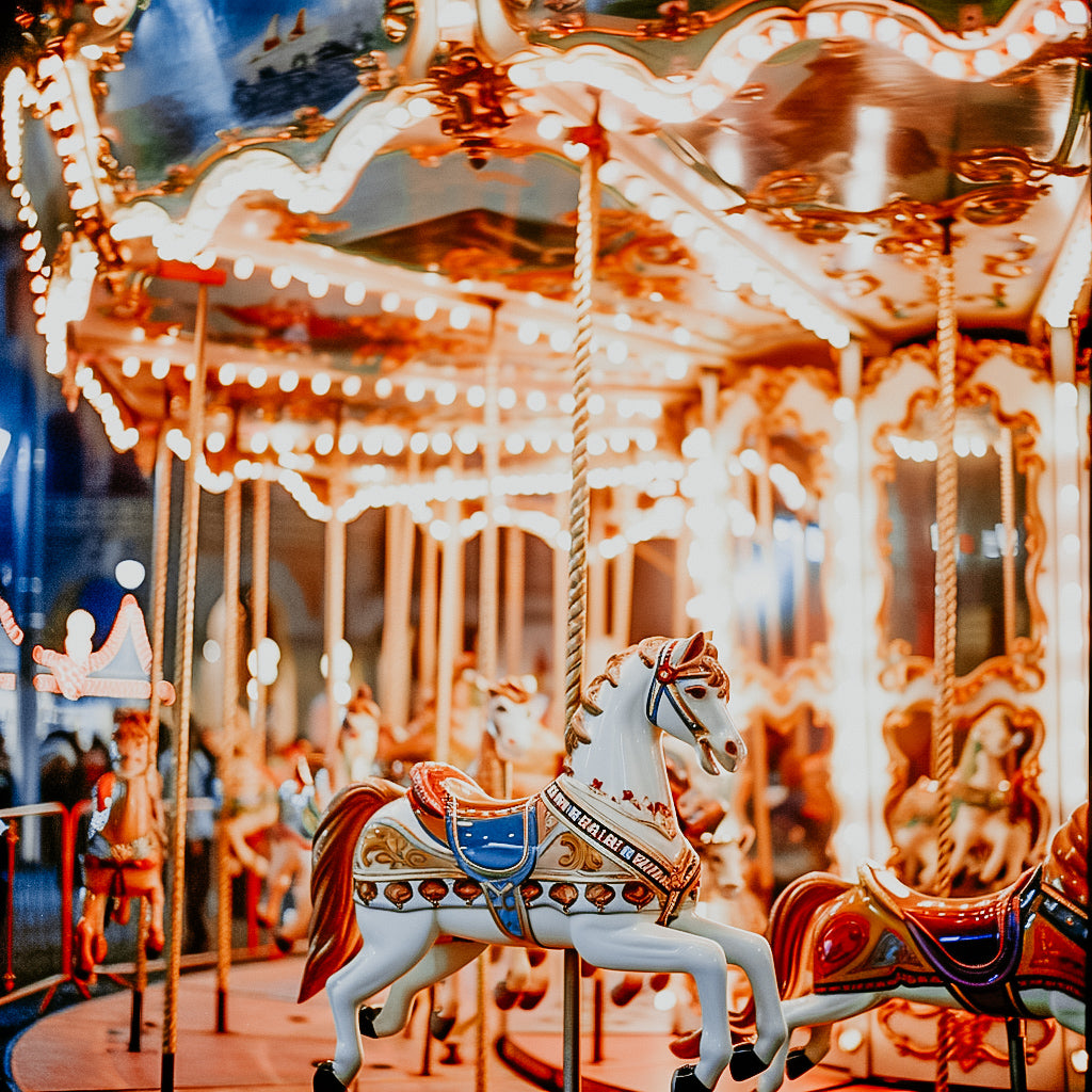 A colorful carousel with ornate horse figures, illuminated and enjoyment rides in the background, creating a whimsical and joyful atmosphere.