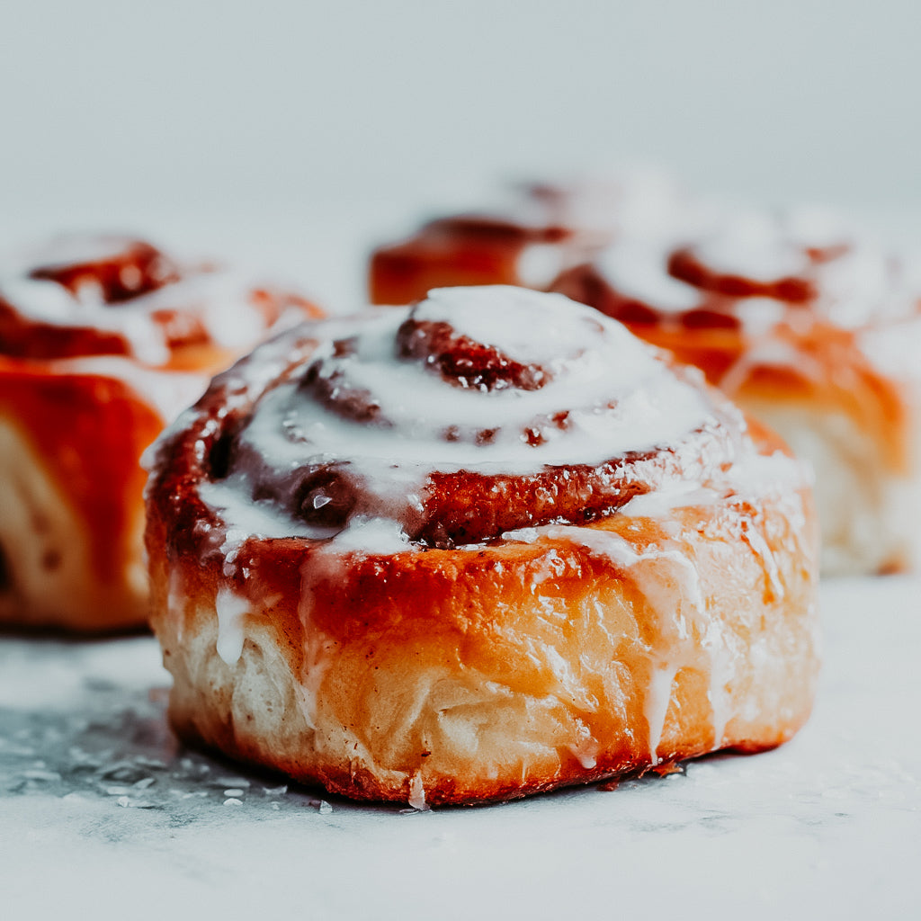 A photo of delicious cinnamon rolls with vanilla icing, showcasing their golden-brown color and garnished with cinnamon sugar.