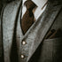A close-up of a man wearing a grey tweed suit with a white shirt and a brown tie, representing the 'Dapper Man' fragrance oil.