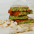 Stack of chocolate bars with green nougat on a marble surface with pistachios.