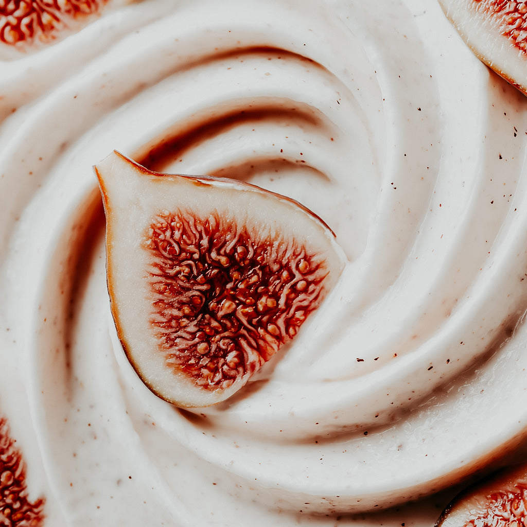 Close-up of a sliced fig on top of whipped cream