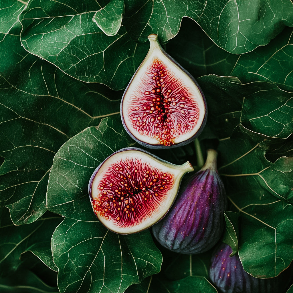 A photograph of a halved fig showing the red flesh and seeds, surrounded by whole figs and green leaves in the background.