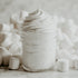 Glass jar filled with white cream against a soft focus background of marshmallows