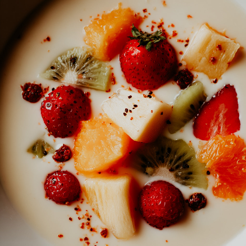 Fruit salad with strawberries, kiwis, and oranges on a white plate.