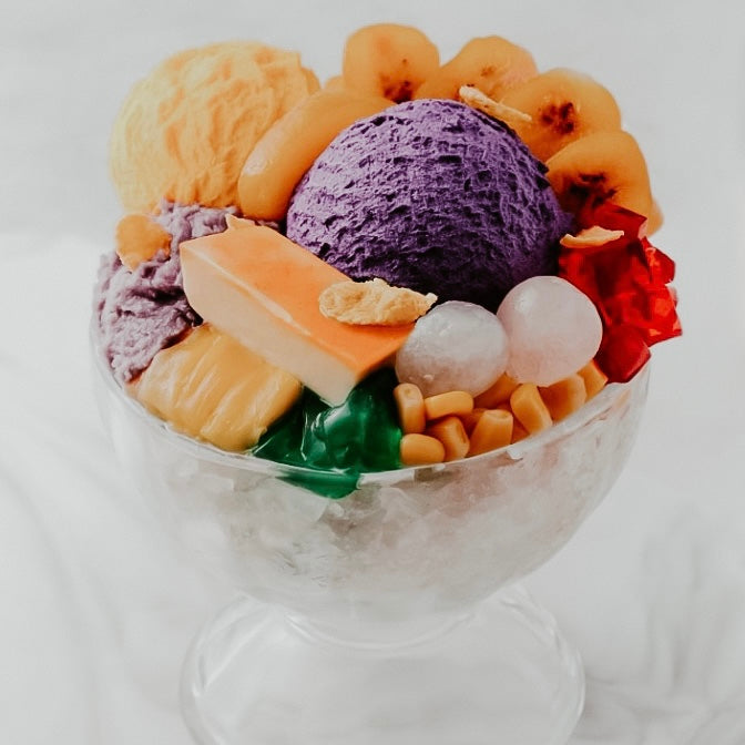 A bowl of halo-halo dessert which includes various sweet components such as ice cream, fruits, and jellies.