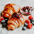 Croissant with jam and berries on a marble surface