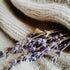 A bundle of dried lavender flowers resting on a beige, knit fabric surface.