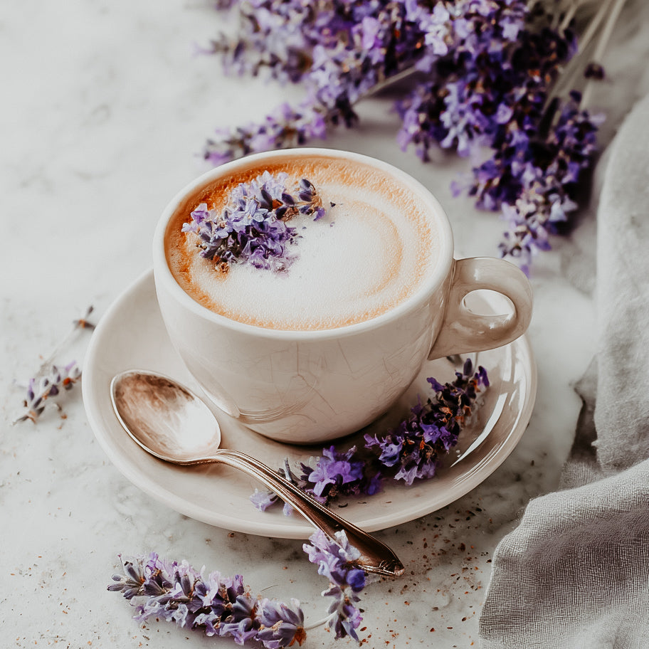 Cappuccino with lavender flowers on a stone surface.