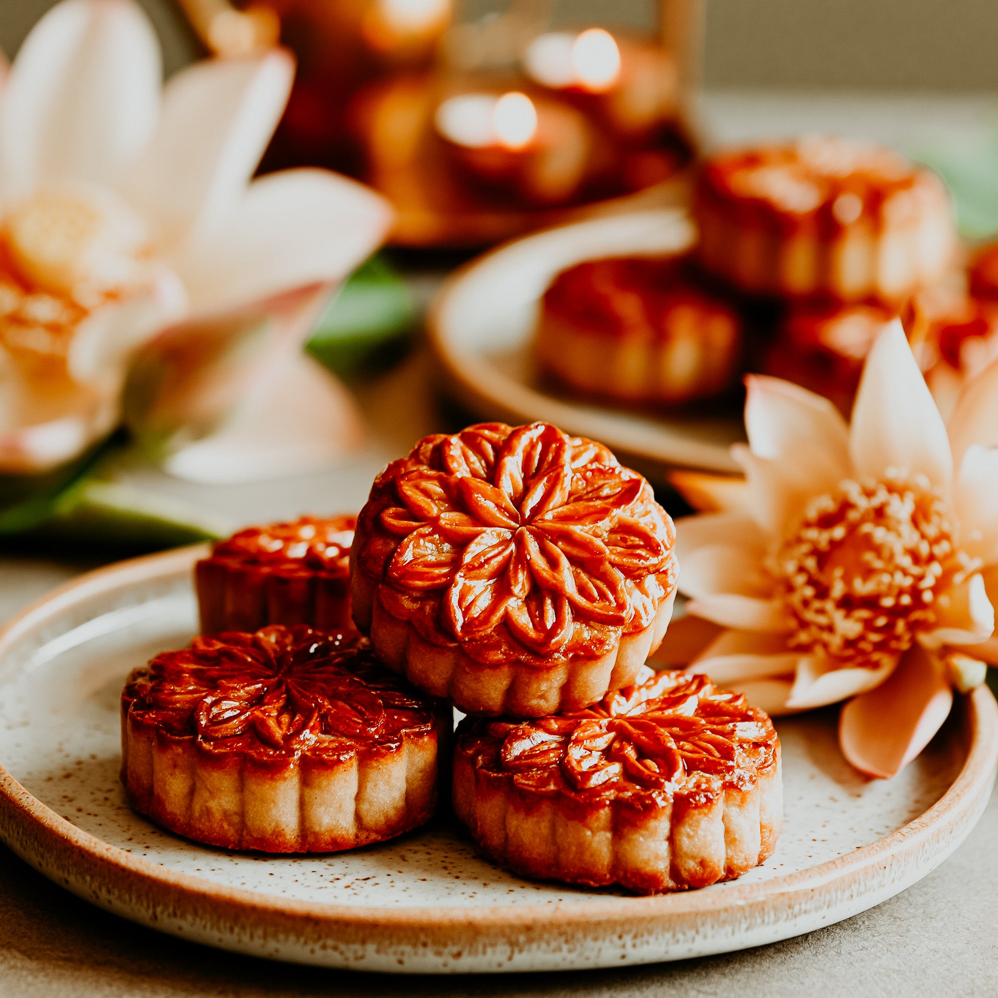 Mooncakes on a plate with flowers and candles in the background