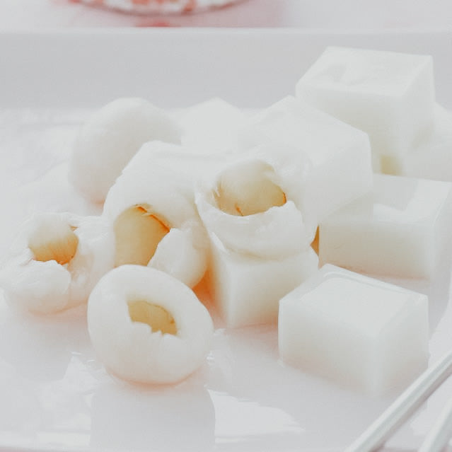 A photo of lychee jelly pieces on a white surface.