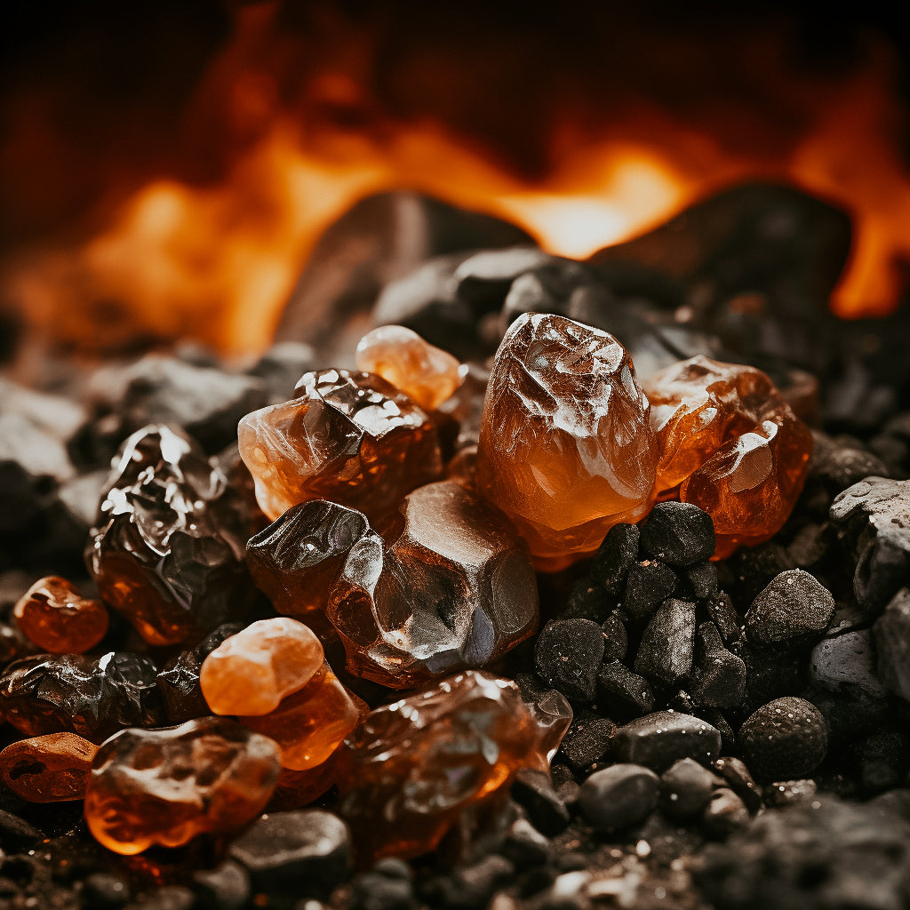 A close-up image of dark, translucent resin pieces on a bed of charcoal, with flames in the background, suggesting a smoky fragrance.