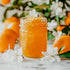 A jar of orange marmalade with a background of fresh oranges and orange blossoms.