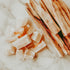 A collection of palo santo wood and white crystals on a marble surface.