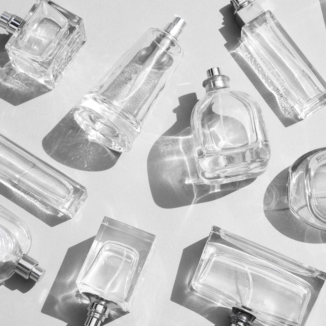 Multiple clear perfume bottles arranged on a light background.
