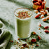 Glass of pistachio milk with nuts on a textured surface