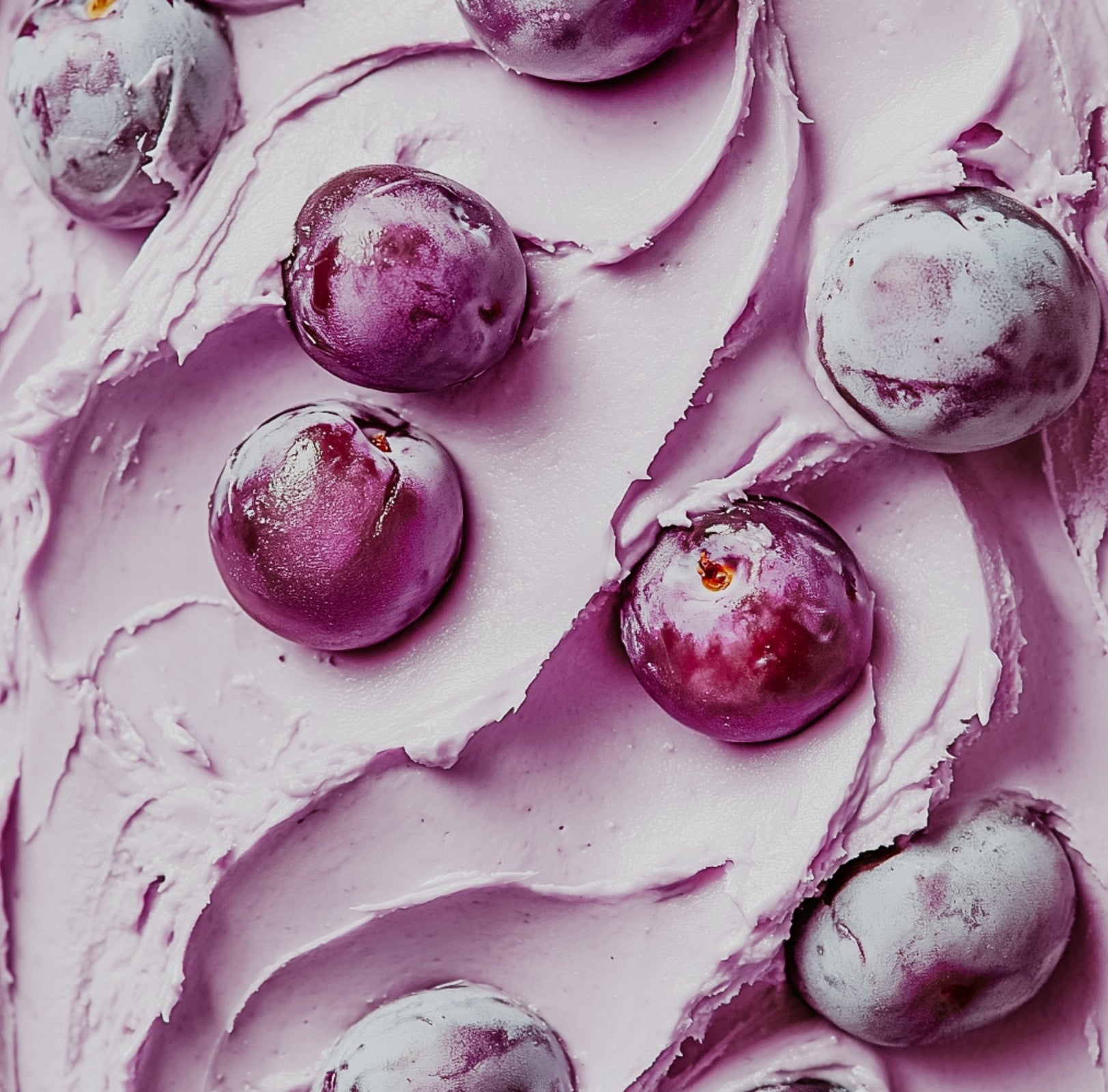 A close-up image creamy texture, featuring what appears to be plum butter or possibly a floral element, providing a visual hint of the fragrance's rich and indulgent scent.