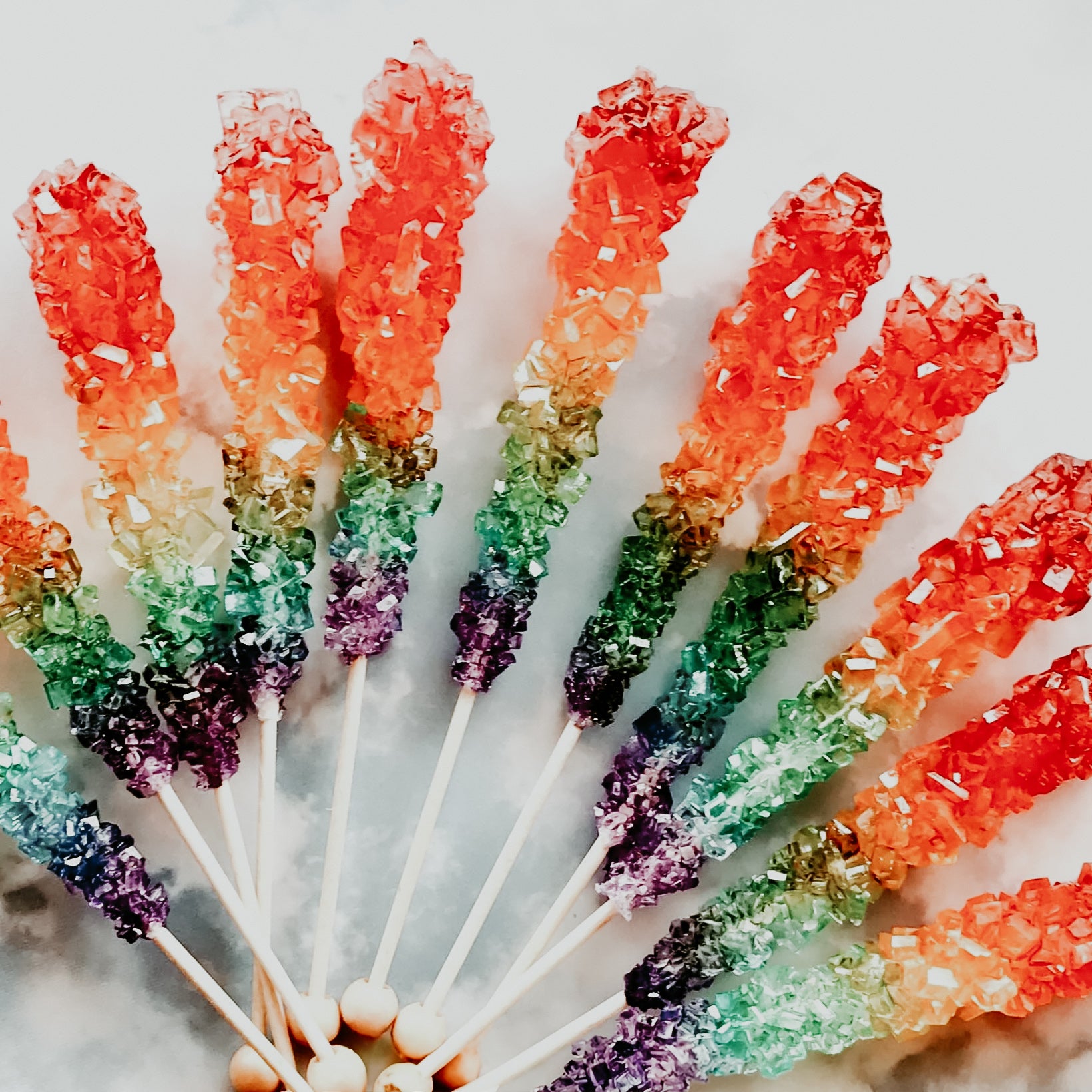 A collection of colorful rock candy sticks fanned out, with a range of colors visible at the tips of each stick.