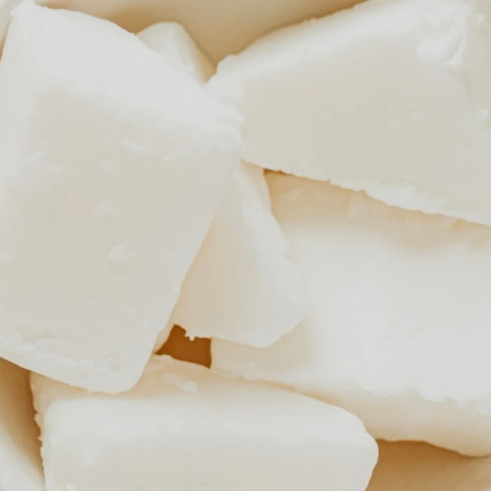 A close-up image of pieces of Luxe Coconut-Apricot Wax from Sozo Essentials, showing a creamy off-white appearance.