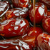A close-up image of dates being drizzled with caramel syrup, highlighting their glossy texture.
