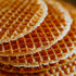 A close-up image of stacked stroopwafels, which are Dutch waffle cookies, showcasing their golden-brown grid-like pattern.