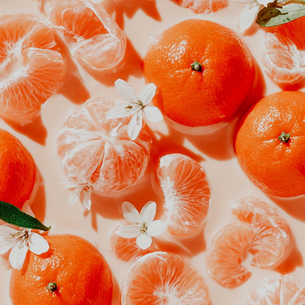 Tangerines and their segments with white flowers on a light background