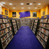 DVD shelves arranged in a store with color-coded sections for new releases, action, drama, and more.