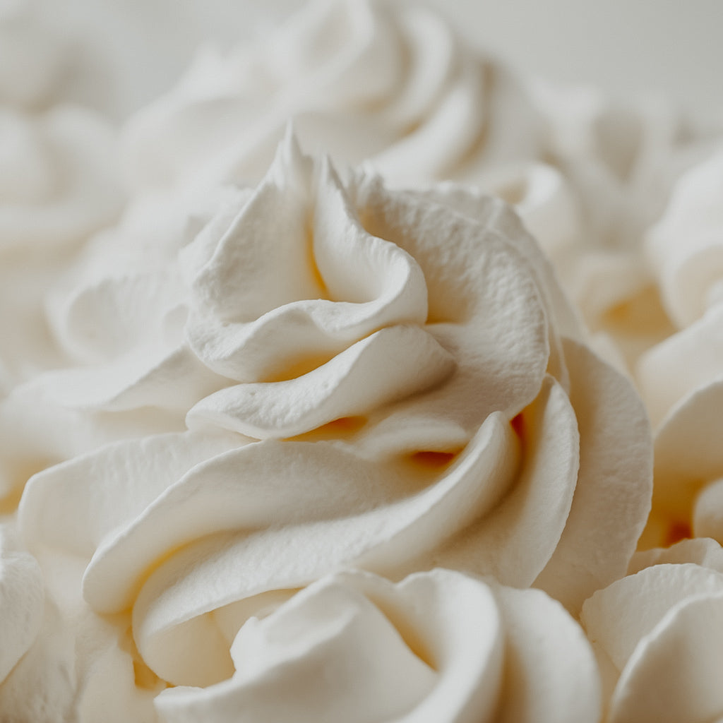 A close-up image of whipped vanilla cream, looking fluffy and cloud-like.