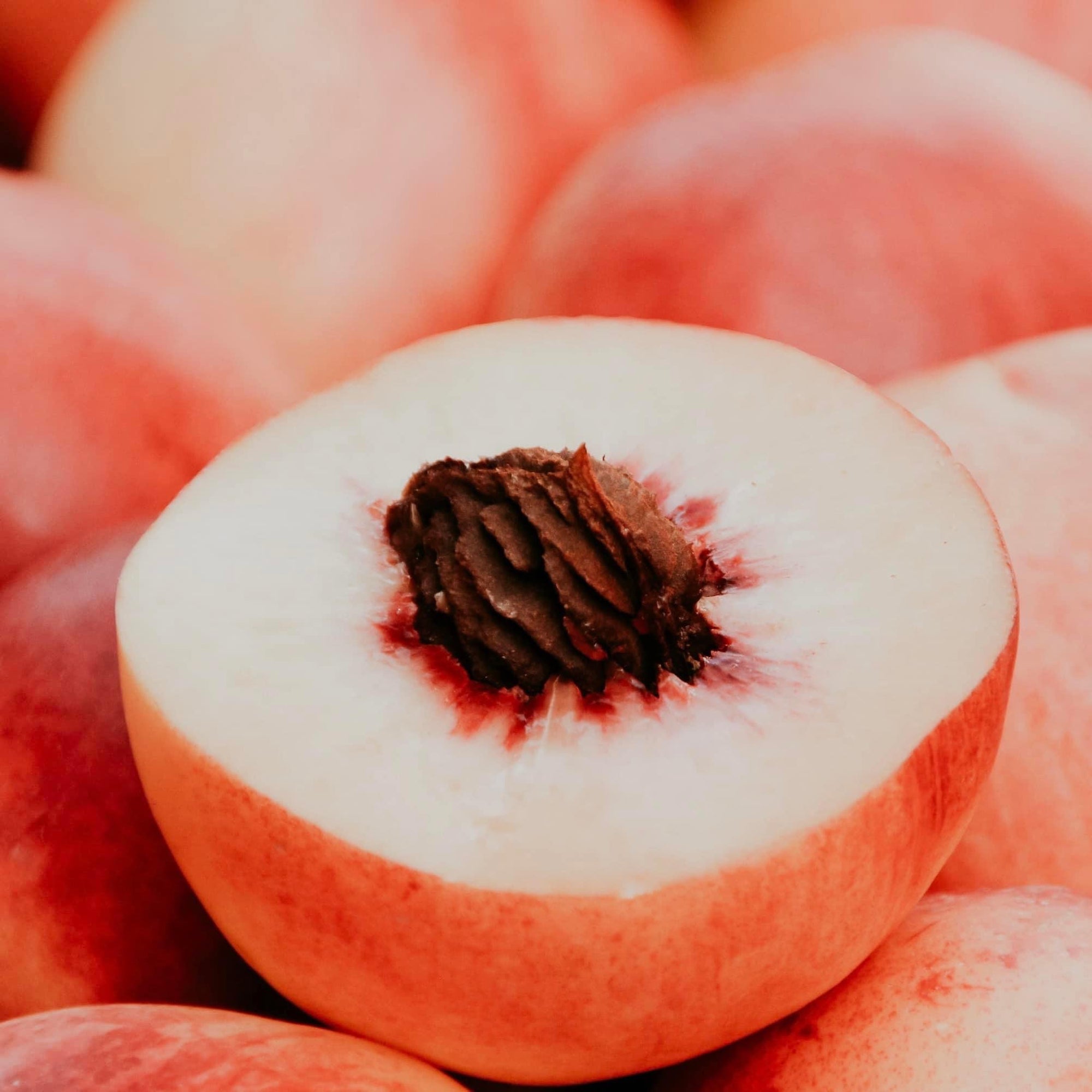 A close-up image of a halved peach, showing the inner flesh and seed.