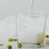 A glass filled with milk being poured, with cardamom pods scattered around.