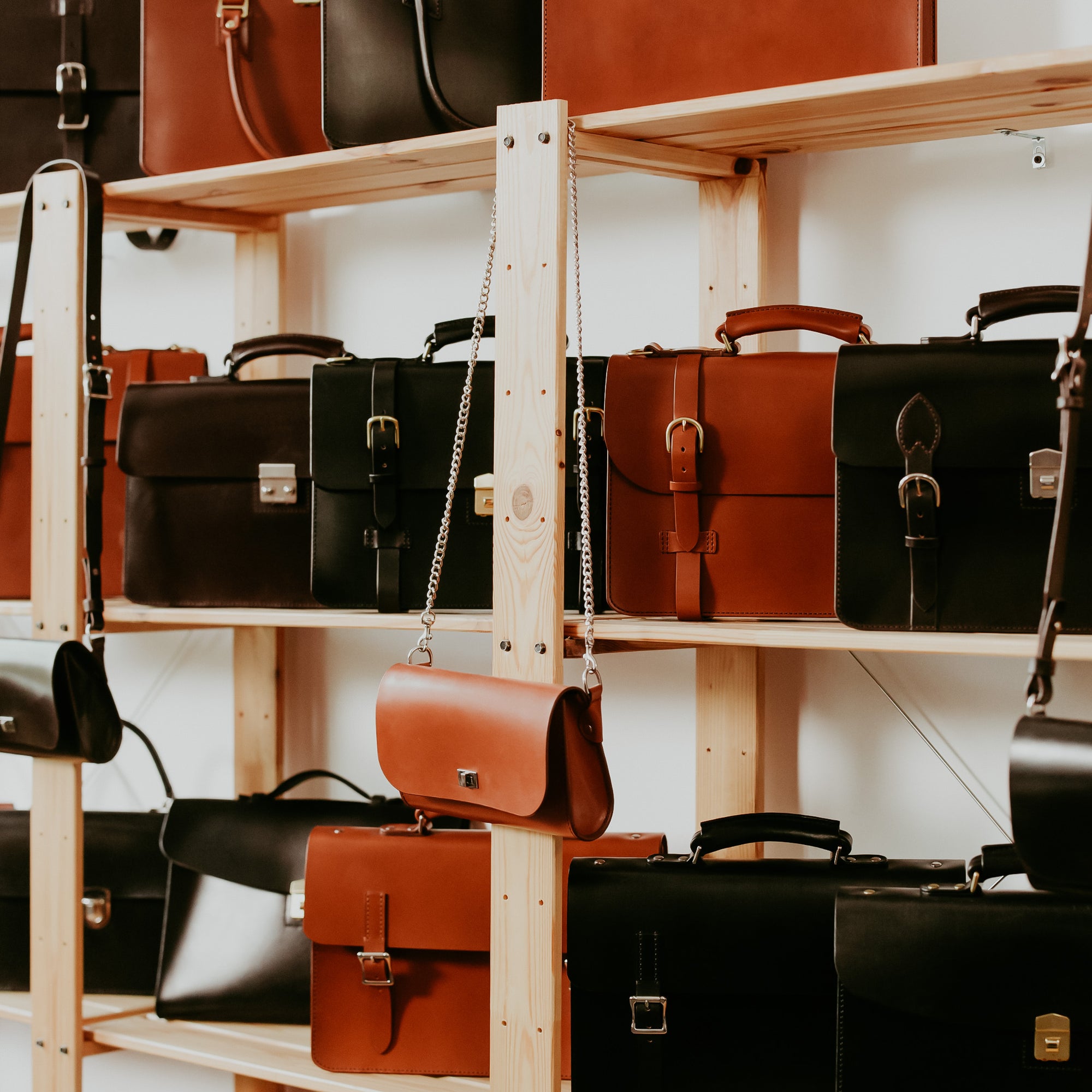 Shelves filled with various leather bags in black, brown, and tan colors.