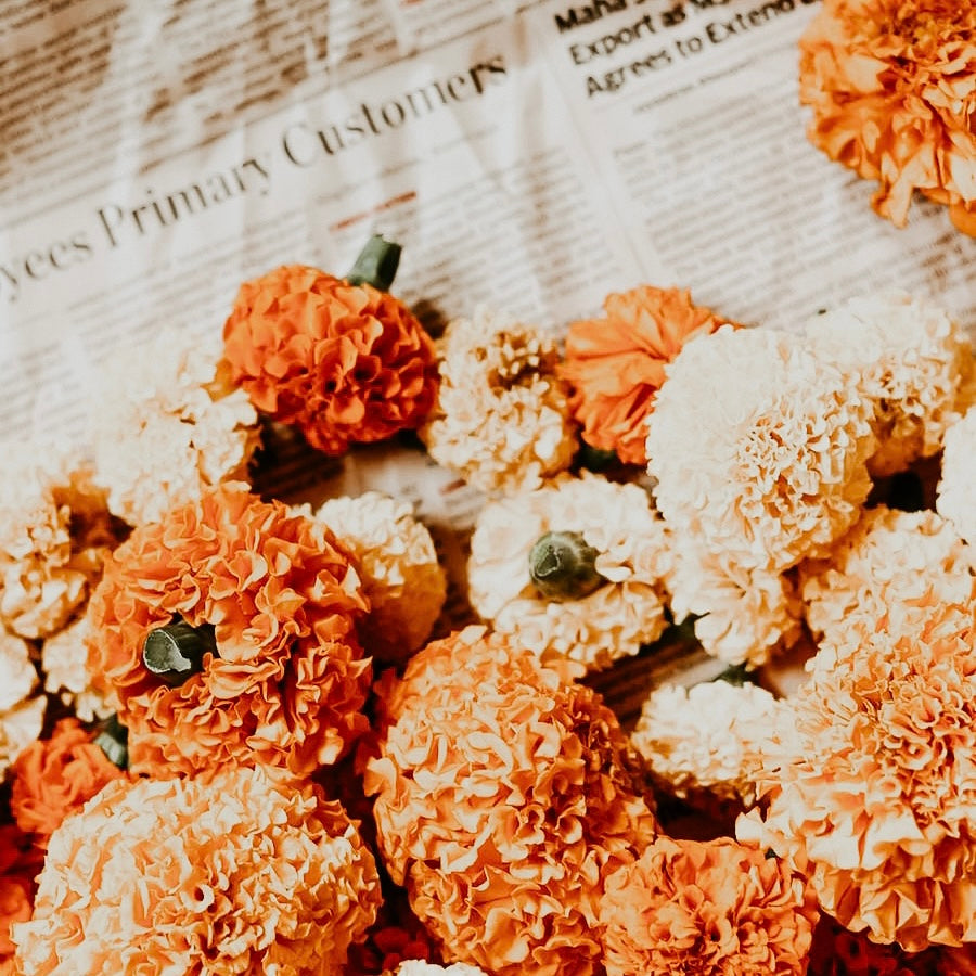 A photo of orange and yellow marigolds laying on top of newspaper