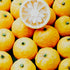 A collection of whole, fresh yuzu fruits with one cut in half to show the inside, arranged closely together.