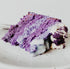 A piece of ube cake with purple layers and vanilla frosting on a plate.